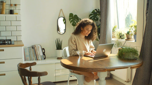 Woman online plant shopping in home filled with indoor plants