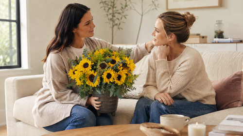 Yellow sunflower bouquet with eucalyptus in a ceramic vase on a living room couch